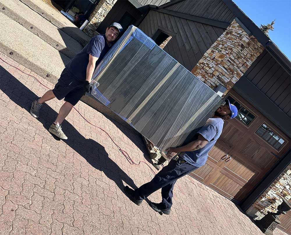 Alberta Pro Movers team carrying a large piece of wrapped furniture during a residential move